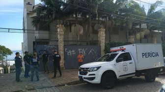 Carro da perícia parado na rua com peritos ao fundo