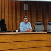Homem falando ao microfone em um auditório 