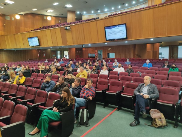 Pessoas sentadas em poltronas de um auditório