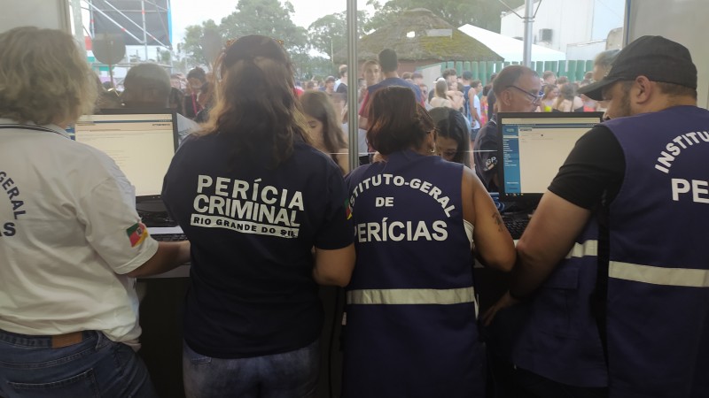 Quatro pessoas com camiseta e jaleco do IGP dentro do Posto com pessoas ao fundo