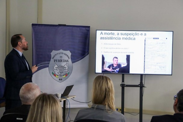 Palestrante ao lado de um dos slides apresentados durante o evento.