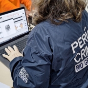 Fotografia mostra servidora com jaqueta do IGP coletando digitais de detenta