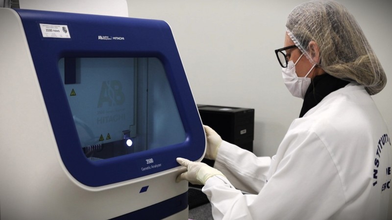 Imagem mostra perita do Instituto-Geral de Per&iacute;cias operando equipamento do laborat&oacute;rio de gen&eacute;tica forense.
